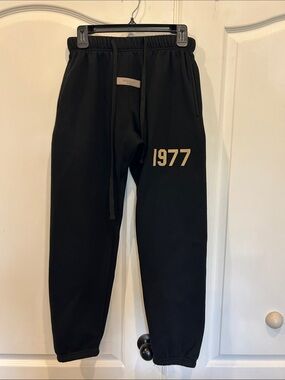 Fear of God Essentials Black Sweatpants with Gold '1977' Print FOG Sweats